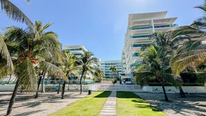 Ein modernes Hotel mit einem zentralen Weg, Palmen und blauem Himmel.