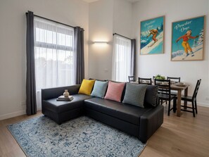 Una sala de estar moderna con un sofá modular, una mesa de comedor y dos cuadros en la pared.