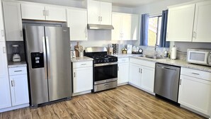 Une cuisine moderne avec des meubles blancs, des appareils en acier inoxydable, une cuisinière à gaz et un lave-vaisselle.