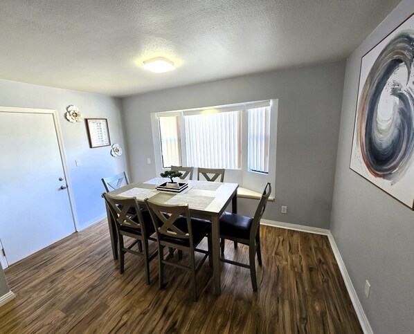 A dining area with a wooden table, four chairs, a small potted plant, and a framed menu on the wall. - Double the Fun! 2 San Diego Homes + Gameroom Near Beach/City/Zoo (San Diego)