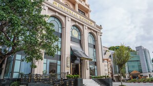 Un edificio imponente con el letrero "Imperial Hotel" en la entrada, que presenta amplias ventanas en arco y una gran escalera que conduce a la puerta.