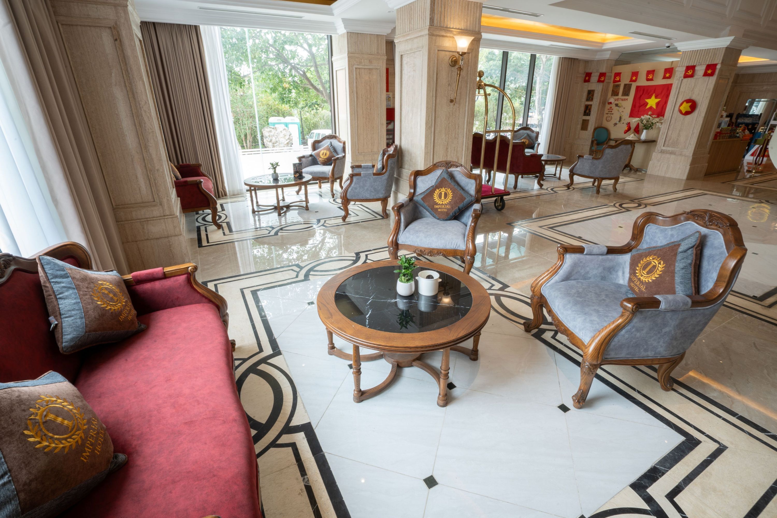 A spacious lobby with a red sofa, wooden armchairs, and a marble floor.