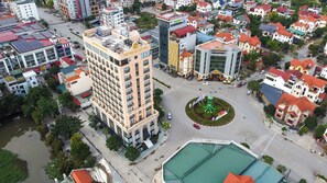 Vista aérea de un paisaje urbano con un hotel destacado que presenta un patio central con una fuente, rodeado de varios edificios y calles.