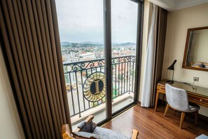 Una habitación con un ventanal grande, un escritorio, una silla y una cama.