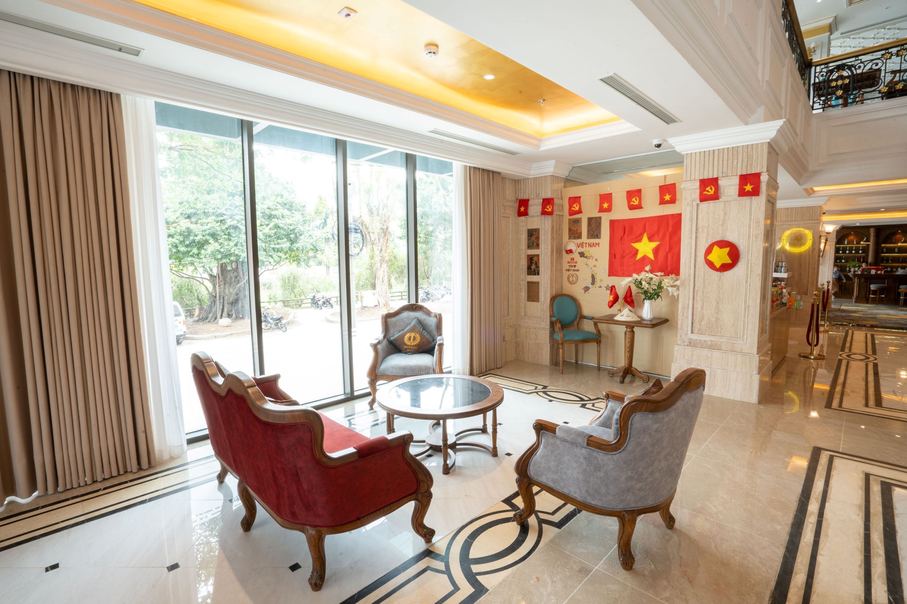 A lobby with a large window, two armchairs, a round table, and a decorative wall with flags.