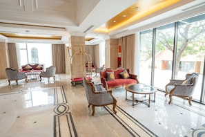 Un vestíbulo espacioso con piso de mármol pulido, muebles elegantes y ventanas amplias con vistas al exterior.