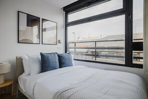 Enjoy a city view from the large bed, surrounded by abstract artworks and a convenient nightstand with a lamp.