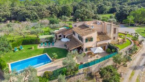 Eine Villa mit Swimmingpool, Sitzgelegenheiten im Freien und Blick auf die umliegende Grünfläche und Hügellandschaft.