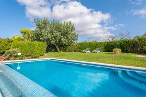 A clear blue swimming pool with a tiled edge, surrounded by a well-maintained lawn and trees. - REYNES - Rustic villa with private pool and free Wi-Fi (Pollença)