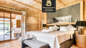 A wooden interior with a bed, bench, and a framed picture on the wall. - Chalet GM - Gardenappartment (Brand)