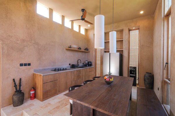 Une cuisine moderne avec des meubles en bois, un îlot central, des luminaires suspendus et une table à manger.