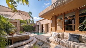 Un espacio exterior moderno con piscina, mobiliario de exterior y ventanas amplias.