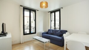 Un salon moderne comprenant un canapé, une table basse, une table à manger et un téléviseur posé sur un meuble.