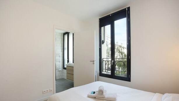 Une chambre à coucher avec un lit, une fenêtre donnant sur un beau paysage et une porte menant à une autre pièce.
