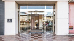 The entrance to Hotel Fujiyoshi with a glass facade and a checkered tile floor.