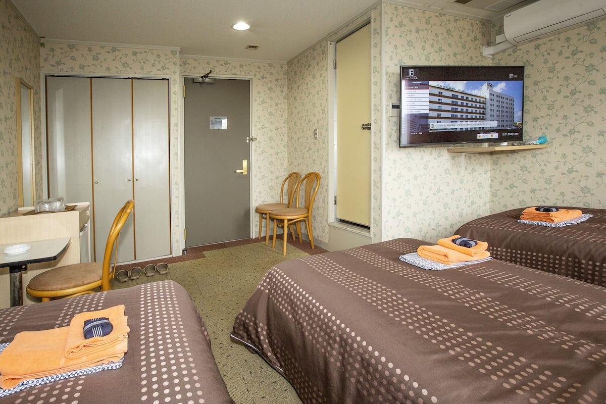 A hotel room with two beds, a TV, a desk, and a chair.
