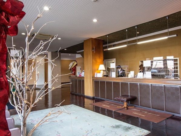 A hotel reception area with a modern design, including a reception desk, seating area, and decorative elements like a tree with lights. - Hotel Fujiyoshi (Beppu)
