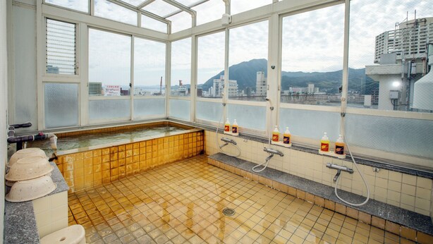 A traditional Japanese onsen with a view of the cityscape through large windows.