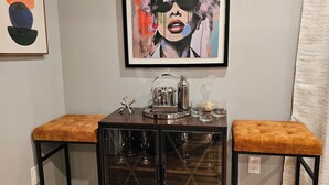 A corner of a room with a black metal cabinet with glass doors, two cushioned stools, and a framed artwork on the wall. - Deluxe Aparment Spacious 3-bedroom apartment with WiFi, AC in nice Elizabeth (Elizabeth)