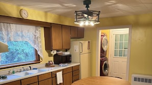 A kitchen with wooden cabinets, a white refrigerator, a microwave, and a dining table with four chairs.
