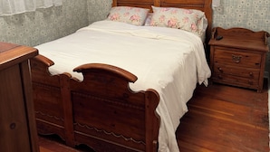 A bedroom with a wooden bed, a nightstand, and a dresser.