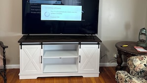A flat-screen TV on a wooden TV stand with a progress bar indicating a software update.