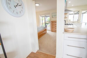 A bedroom with a bed, a wooden dresser, and a wall clock.