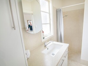 Een badkamer met een wastafel, spiegel en douche.
