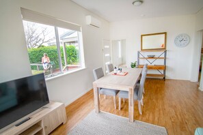 Een moderne woonkamer met een televisie, eettafel en stoelen.
