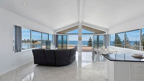 Uma sala de estar ampla, com uma janela grande, um sofá e uma mesa de jantar.