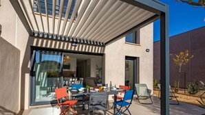 A modern outdoor patio with a dining area, including a table and chairs, and a covered seating area. - Azur Cottages by Interhome (Saint Aygulf)