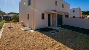 A modern two-story house with a flat roof, a stone accent wall, and a gravel driveway. - Azur Cottages by Interhome (Saint Aygulf)