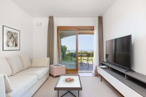 Ein modernes Wohnzimmer mit einer Couch, einem Couchtisch, einem Flachbildfernseher und einer Glastür zum Außenbereich.