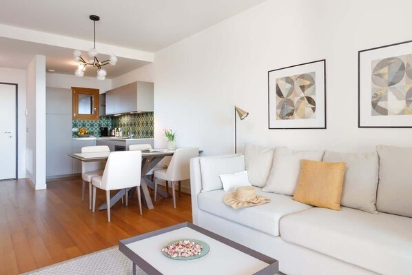 A modern living room with a sofa, coffee table, and dining area.