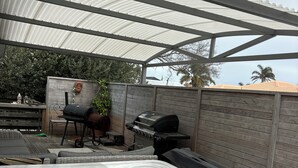 Un espace extérieur abrité comprenant un jacuzzi, un barbecue et un coin salon.