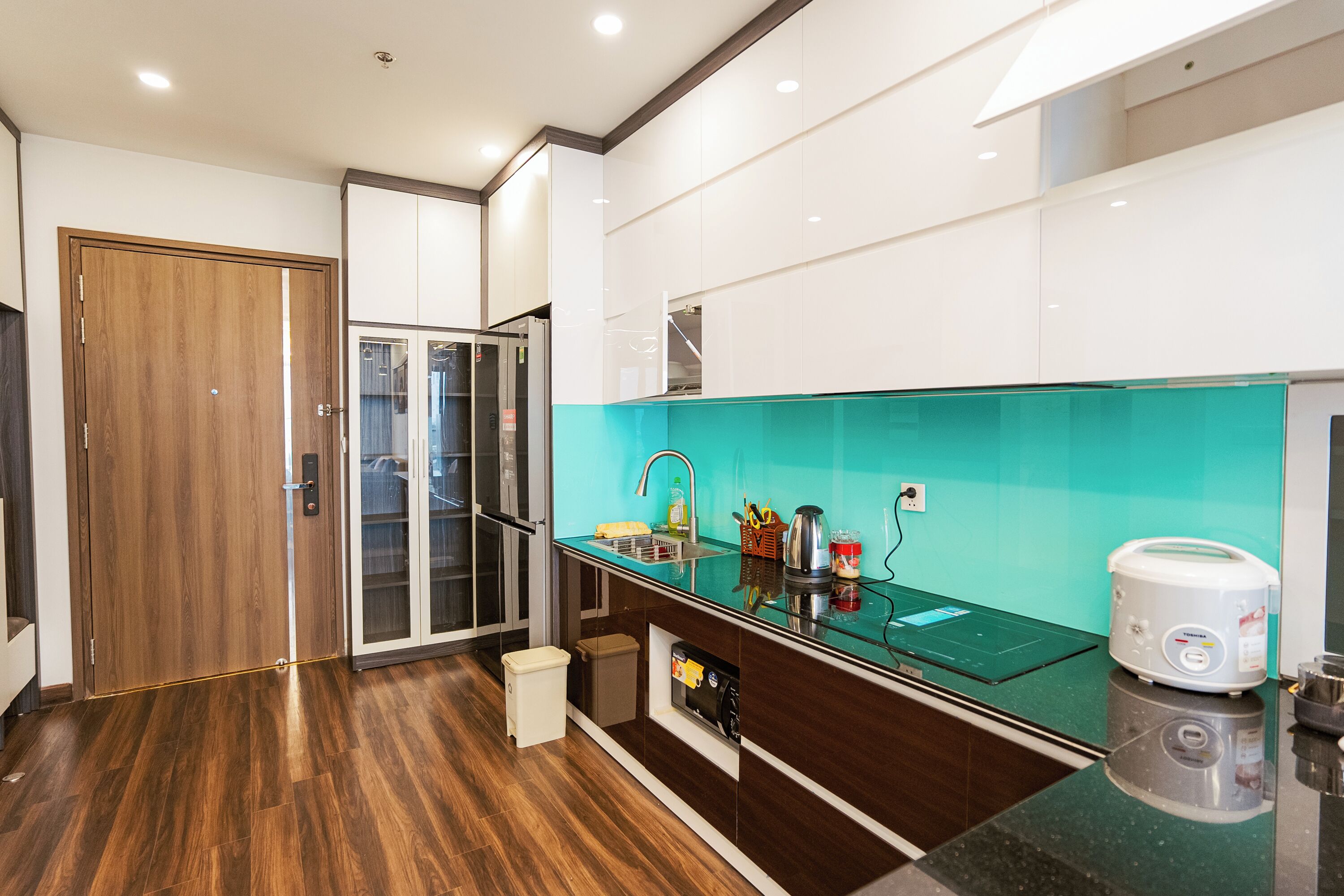 Une cuisine moderne avec une porte en bois, un meuble vitré, un évier et un grille-pain.