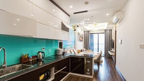 A modern kitchen with a large island, built-in appliances, and a teal backsplash. - X-Stay Luxe (Hai Phong)