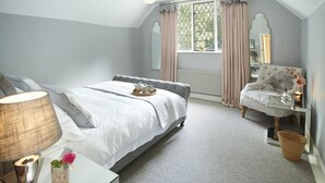 A bedroom with a bed, bedside table, lamp, mirror, and a window with curtains. - Bull Hollow Cottage -  Shrewsbury , Shropshire (Shrewsbury)