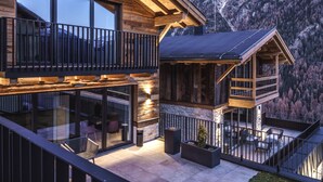 A wooden chalet with a balcony overlooking a mountainous landscape.