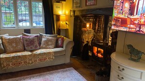 Una sala de estar acogedora con chimenea, un sofá con cojines estampados y un televisor mostrando una escena de bar.