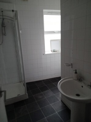 A bathroom with a shower, a sink, and a window. - Sunny Seaside Apartment in Blackpool (Blackpool)
