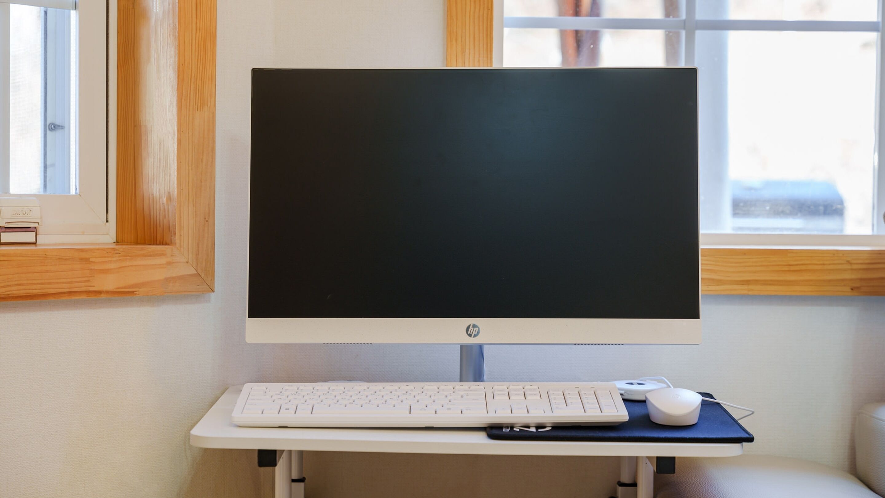 A desktop computer setup with a monitor, keyboard, and mouse on a white desk.