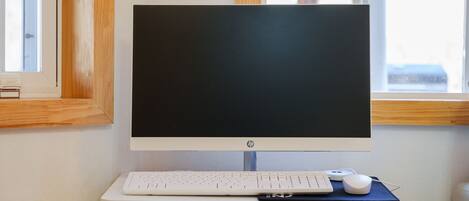 A desktop computer setup with a monitor, keyboard, and mouse on a white desk.