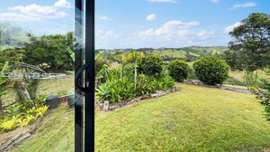 Vista desde una ventana con vistas a un jardín cuidado, con diversas plantas y césped.