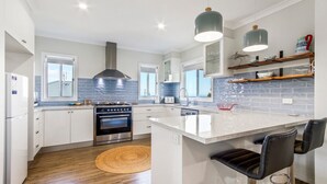 A modern kitchen with white cabinets, a stainless steel oven, and a large island with bar stools.
