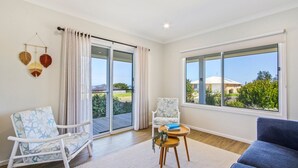 A spacious living room with a large sliding glass door leading to a balcony, two chairs with star patterns, a blue sofa, and a small table with a book and plant.