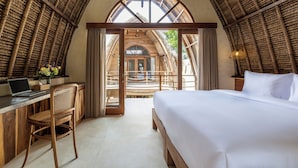 Ein Zimmer mit Bett, Schreibtisch und Stuhl, mit einem großen Bogenfenster und Holzbalkendecke.