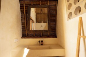 Een badkamer met een spiegel met houten lijst, een wastafel en een handzeepdispenser.