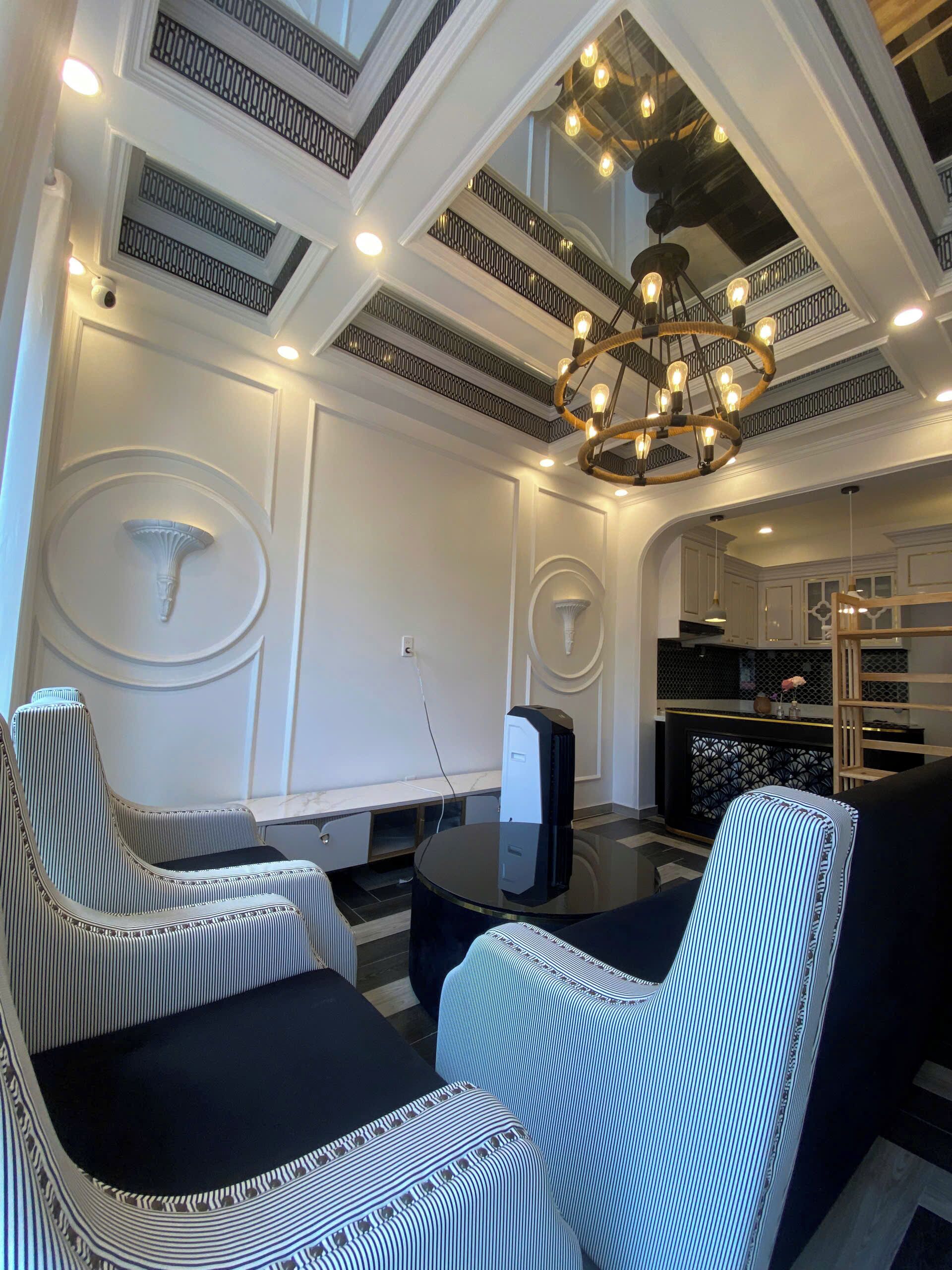 A modern living room with a black and white striped sofa, a round glass coffee table, and a decorative ceiling light fixture.