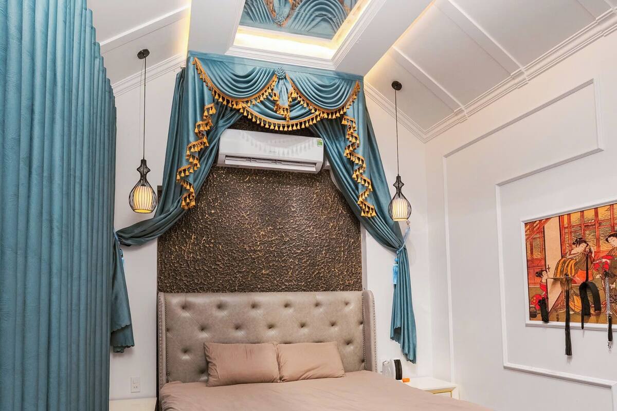 A bedroom with a tufted headboard, a checkered floor, and a decorative canopy over the bed.
